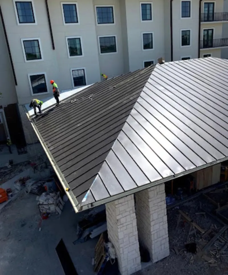 Crew installing standing seam metal roof panels on a commercial project in Bayville